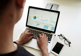 Pessoa trabalhando em um notebook com gráficos de desempenho.