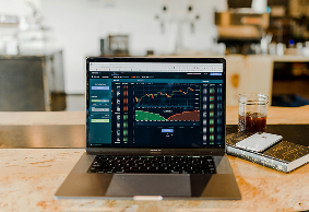 Notebook exibindo painel financeiro em uma mesa de trabalho.
